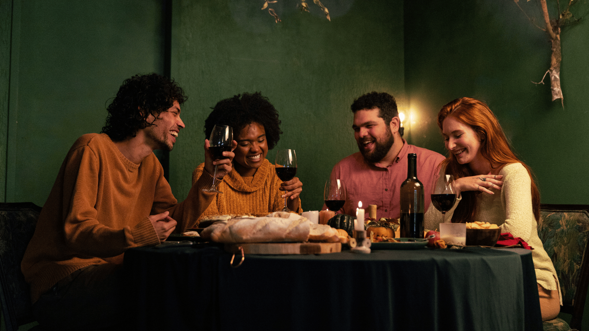 Freunde sitzen beim Abendessen, genießen ein Glas Wein und lachen gemeinsam.